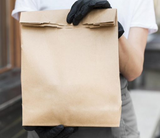 A person holding a bag of items with gloved hands