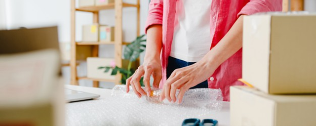 A small fragile item is padded using bubble wrap