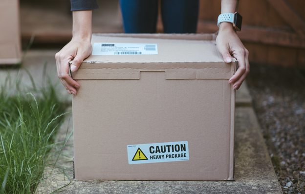 person-resting-his-arms-cardboard-box-with-label-caution-heavy-package