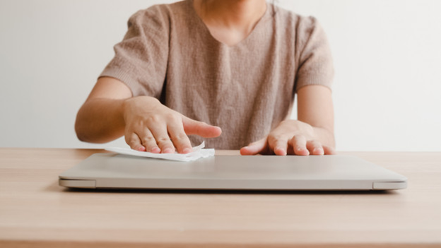 A person wiping down a laptop